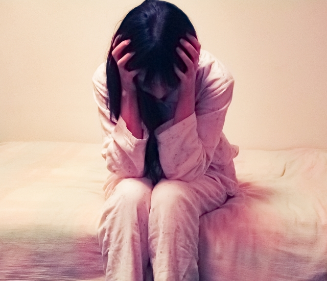 頭をかかえる若い女性